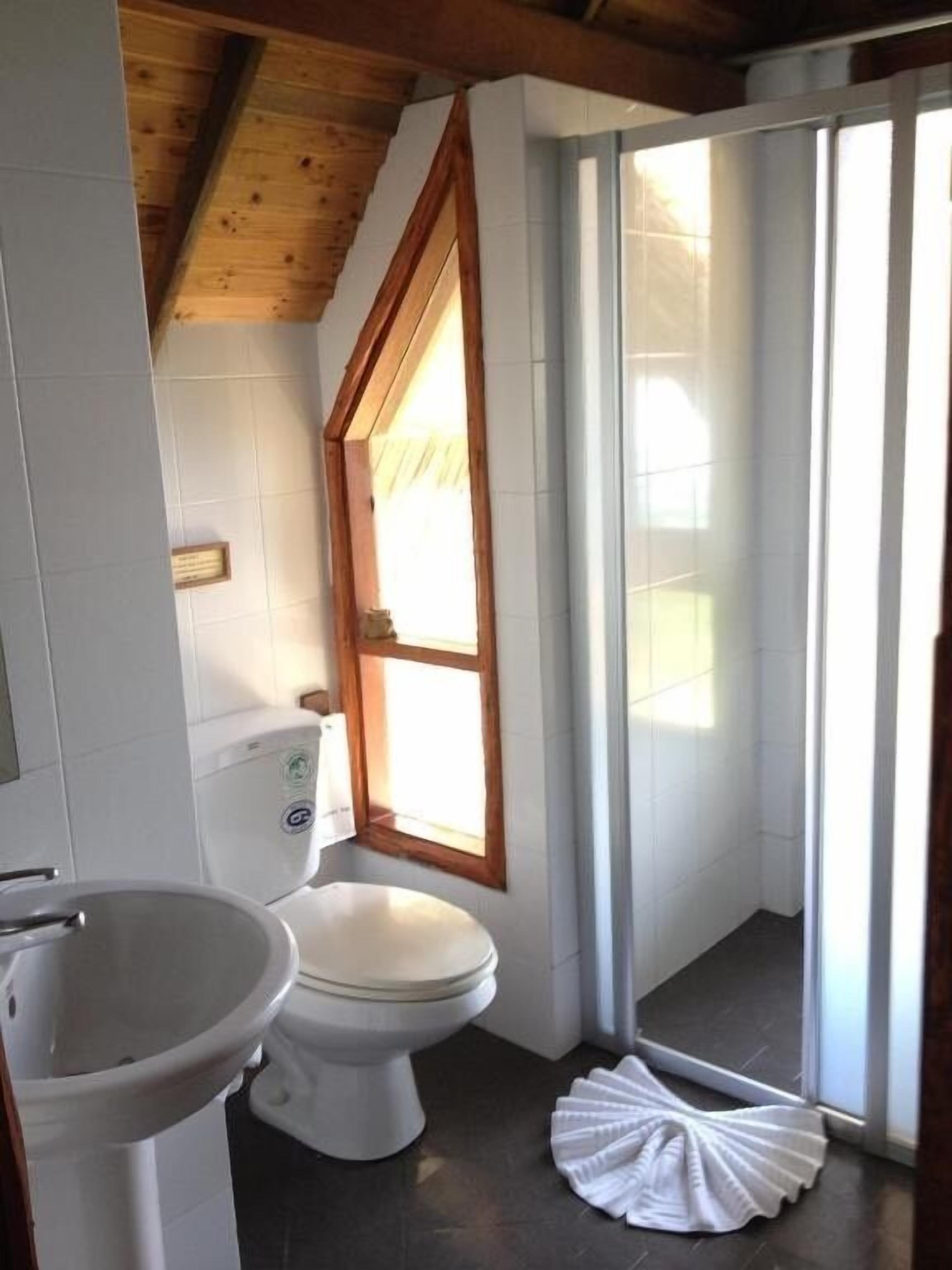 Et lille badeværelse med toilet, vask og et vindue.