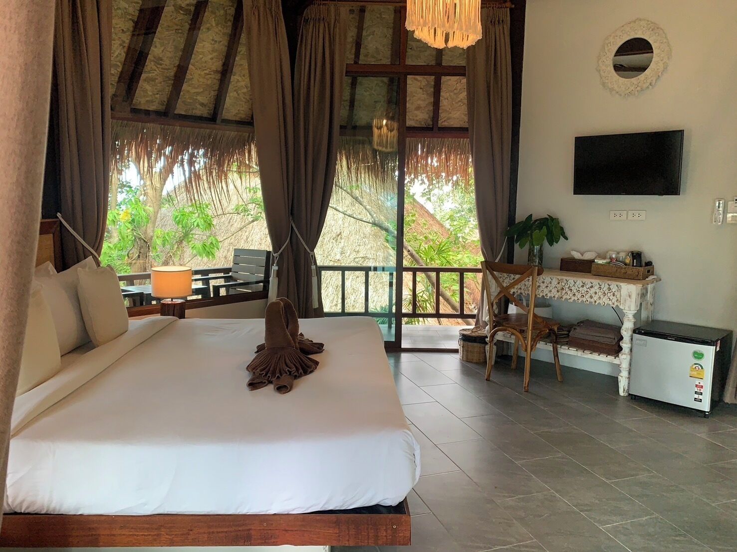 A bedroom with a bed, a TV, a small table, and a chair.