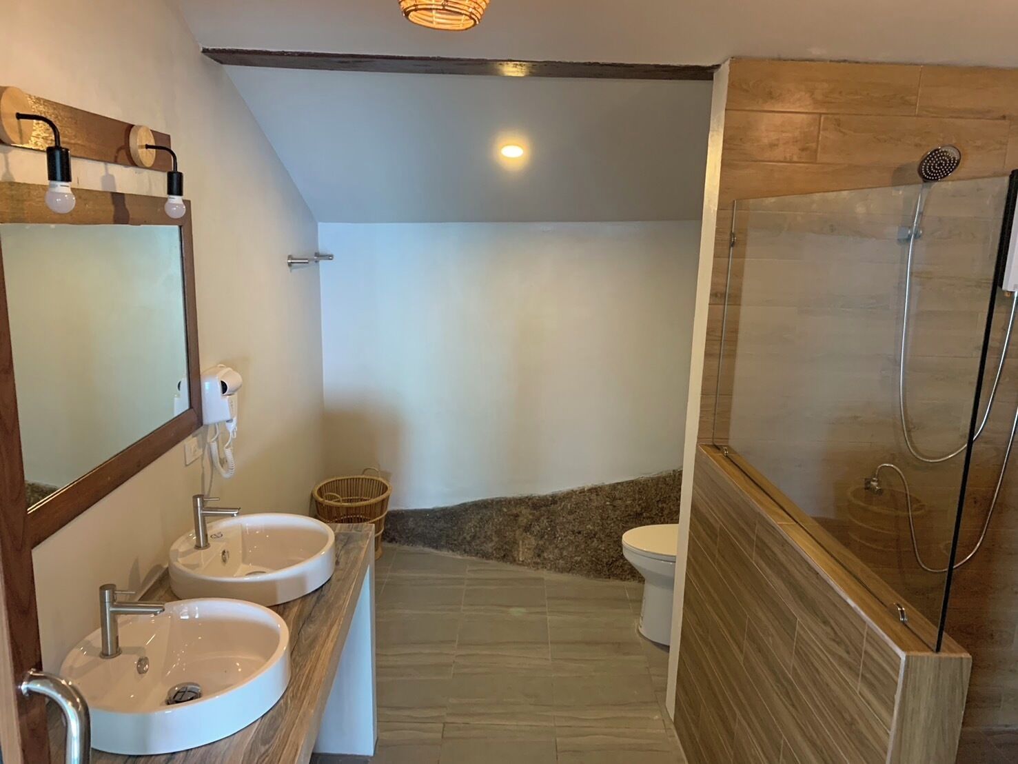 Un baño moderno con dos lavamanos, un espejo, una ducha e inodoro.