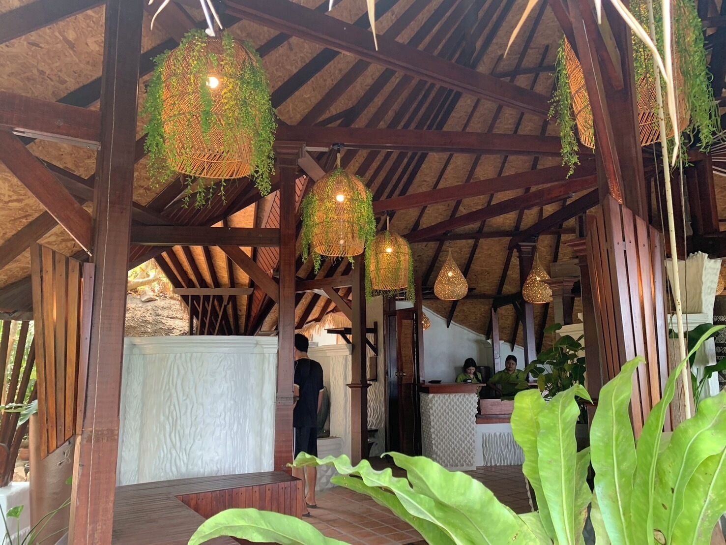 A covered outdoor area with wooden beams and hanging light fixtures.