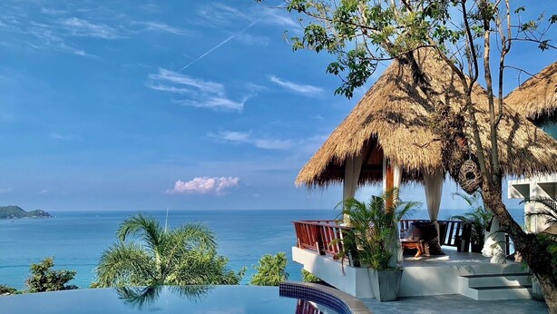 Ein luxuriöser Infinity-Pool mit freiem Blick auf das Meer und einer Struktur mit Reetdach.