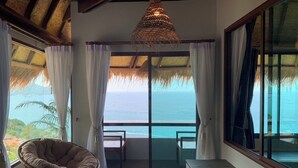 Ein Zimmer mit Meerblick, ein Korbstuhl und eine Hängelampe.
