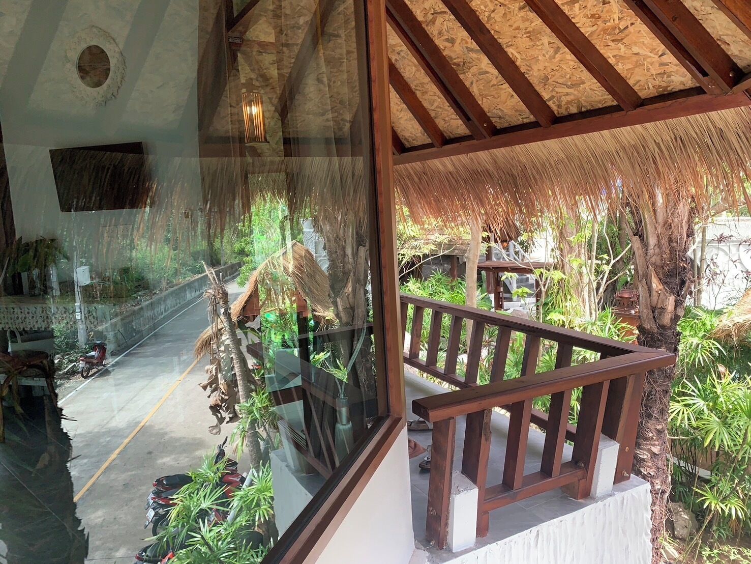 A glass-walled room with a wooden balcony overlooking a garden.