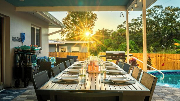 A covered patio with a dining table set for six, a pool, and a barbecue grill. - Mins to beach, heated pool, minigolf, fire pit, arcade, dog friendly (Largo)