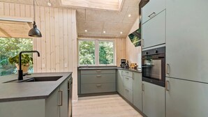 Eine moderne Küche mit großem Fenster, Holzboden und integrierten Geräten.