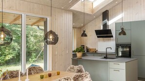 Eine moderne Küche mit Holzvertäfelung, einer zentralen Kochinsel und Pendelleuchten.