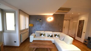 Un salón moderno con un sofá seccional blanco, una mesa de centro de madera y un radiador.