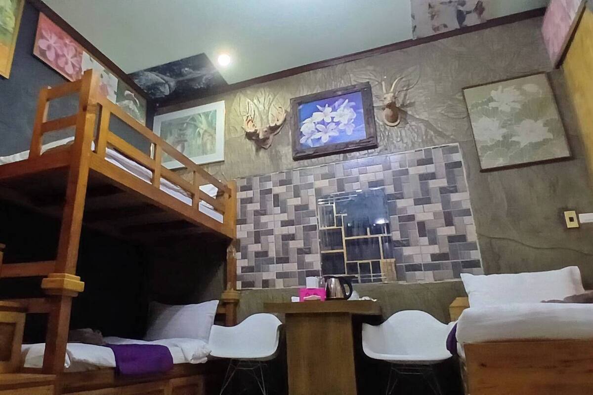 A room with a bunk bed, a small table, two white chairs, and decorative wall art.