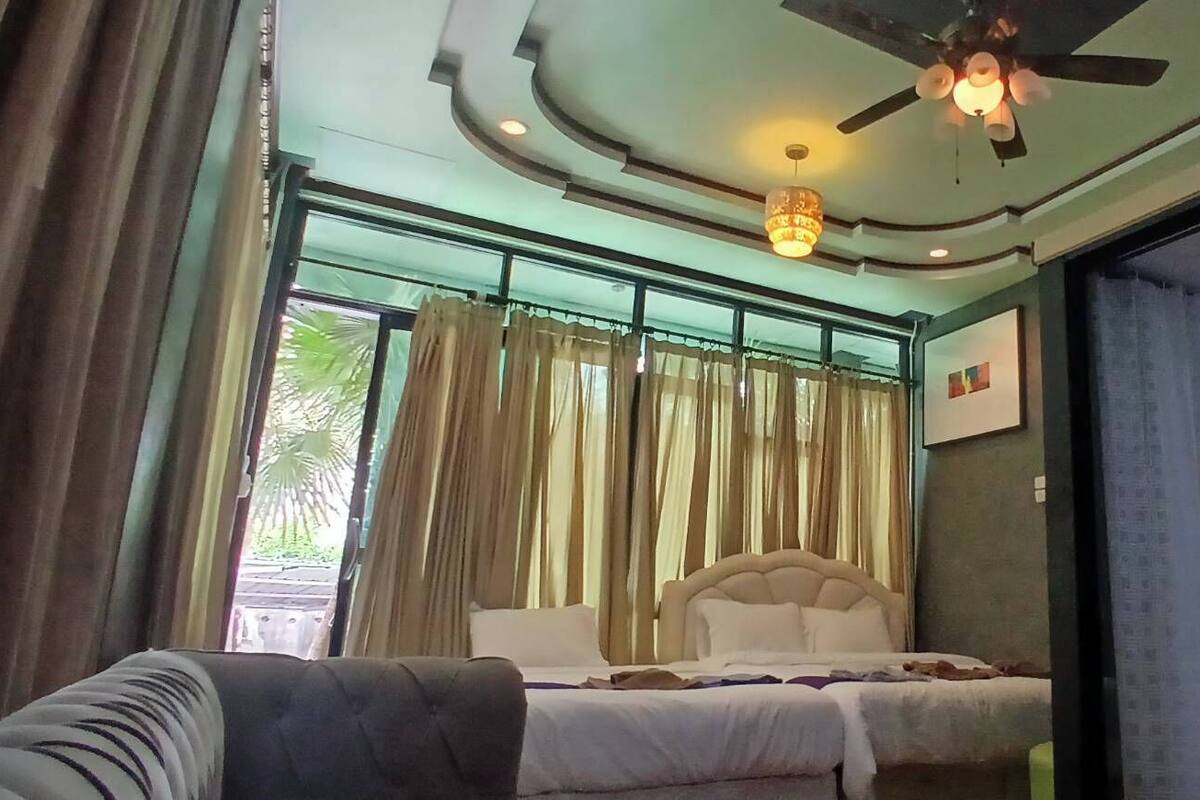 A bedroom with a bed, curtains, a ceiling fan, and a view through a glass door.