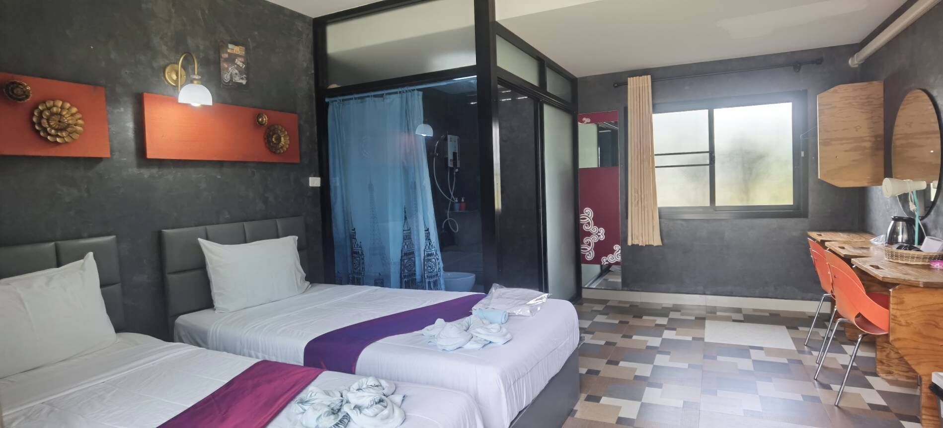 Hotellihuone, jossa on kaksi sänkyä, kylpyhuone ja työpöytä, jossa on peili.