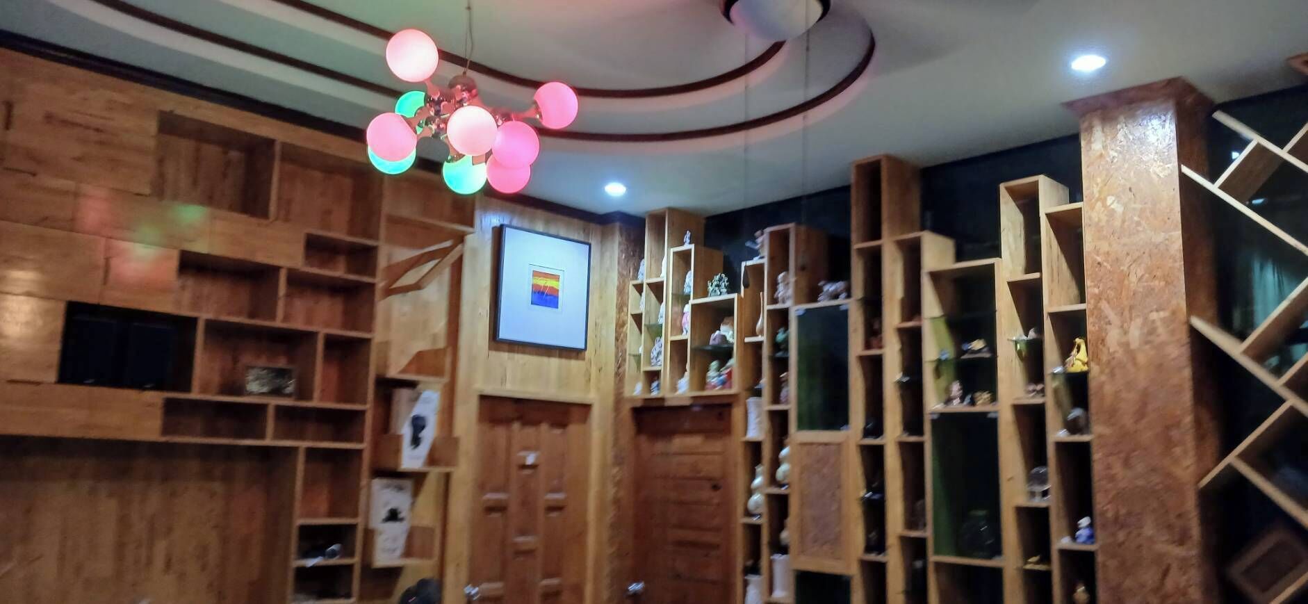 A room with wooden shelving units, a ceiling fan, and a mounted television.