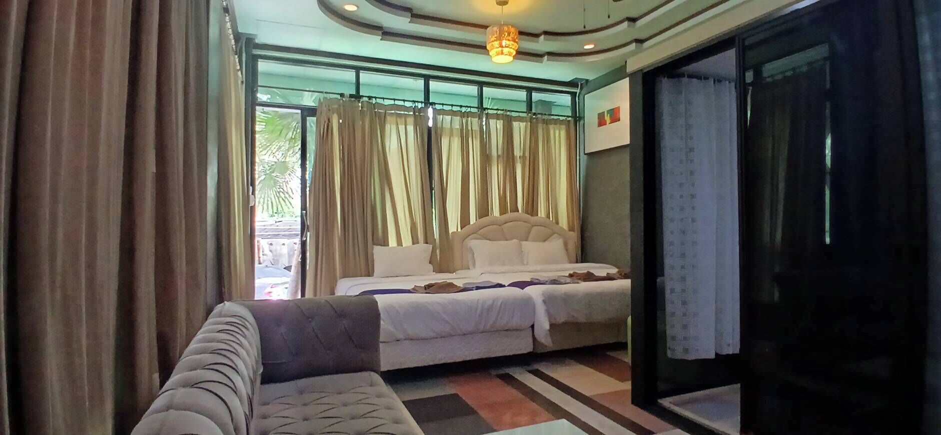 A hotel room with a bed, a sofa, and a large window with curtains.