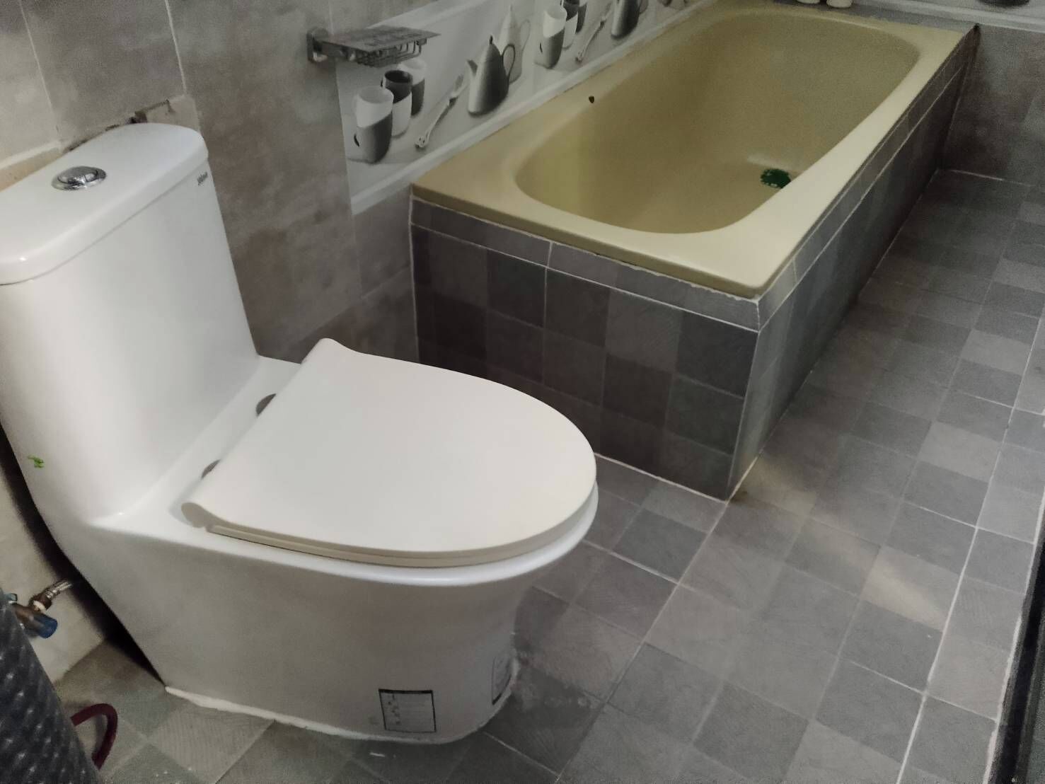 A bathroom with a toilet, a bathtub, and a tiled floor.