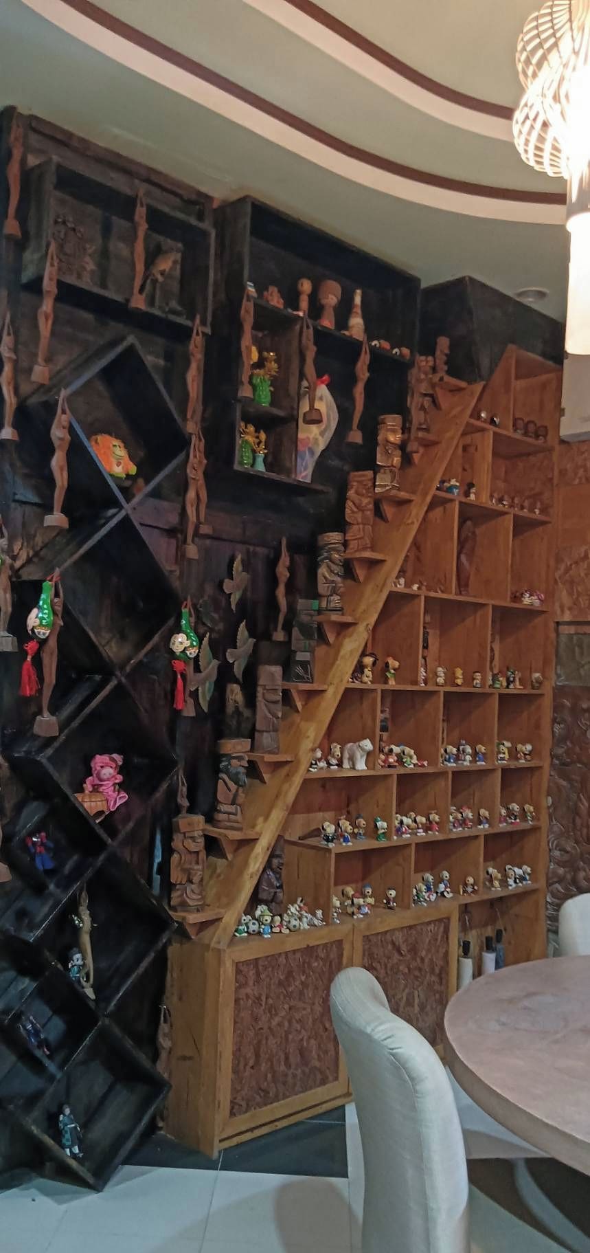 Une pièce dotée d’un escalier en bois menant à une étagère remplie de diverses figurines et de petits objets.