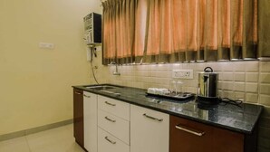 A kitchen with a sink, cabinets, a microwave, and a kettle on the countertop. - Raj Exotic Palms (Vagator)