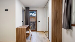 A room with a wooden desk, chair, and a view through a door to a balcony. - Apartment '3' with Mountain View, Shared Garden and Wi-Fi (Valdidentro)
