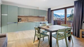 A modern kitchen with a dining area, large windows, and a view of mountains. - Apartment '3' with Mountain View, Shared Garden and Wi-Fi (Valdidentro)