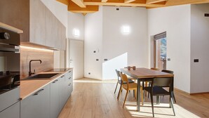 Et moderne køkken med træbordplade, rustfrie stål apparater og et spiseområde med et træbord og stole.