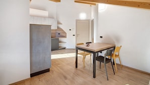 A modern kitchen with a wooden staircase, a dining table with chairs, and a door in the background. - Apartment '6' with Mountain View, Shared Garden and Wi-Fi (Valdidentro)