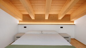 A bedroom with a bed, bedside tables, and a wooden ceiling. - Apartment '6' with Mountain View, Shared Garden and Wi-Fi (Valdidentro)