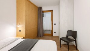 A bedroom with a bed, a chair, a wooden wardrobe, and a door with a curtain. - Apartment '1' with Mountain View, Shared Terrace and Wi-Fi (Isolaccia)