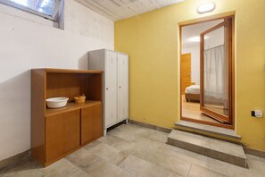 Un couloir avec une armoire en bois, un casier blanc et une porte donnant sur une chambre.