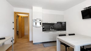 A modern kitchen with white cabinets, a built-in oven, and a flat-screen TV mounted on the wall. - Apartment '1' with Mountain View, Shared Terrace and Wi-Fi (Isolaccia)