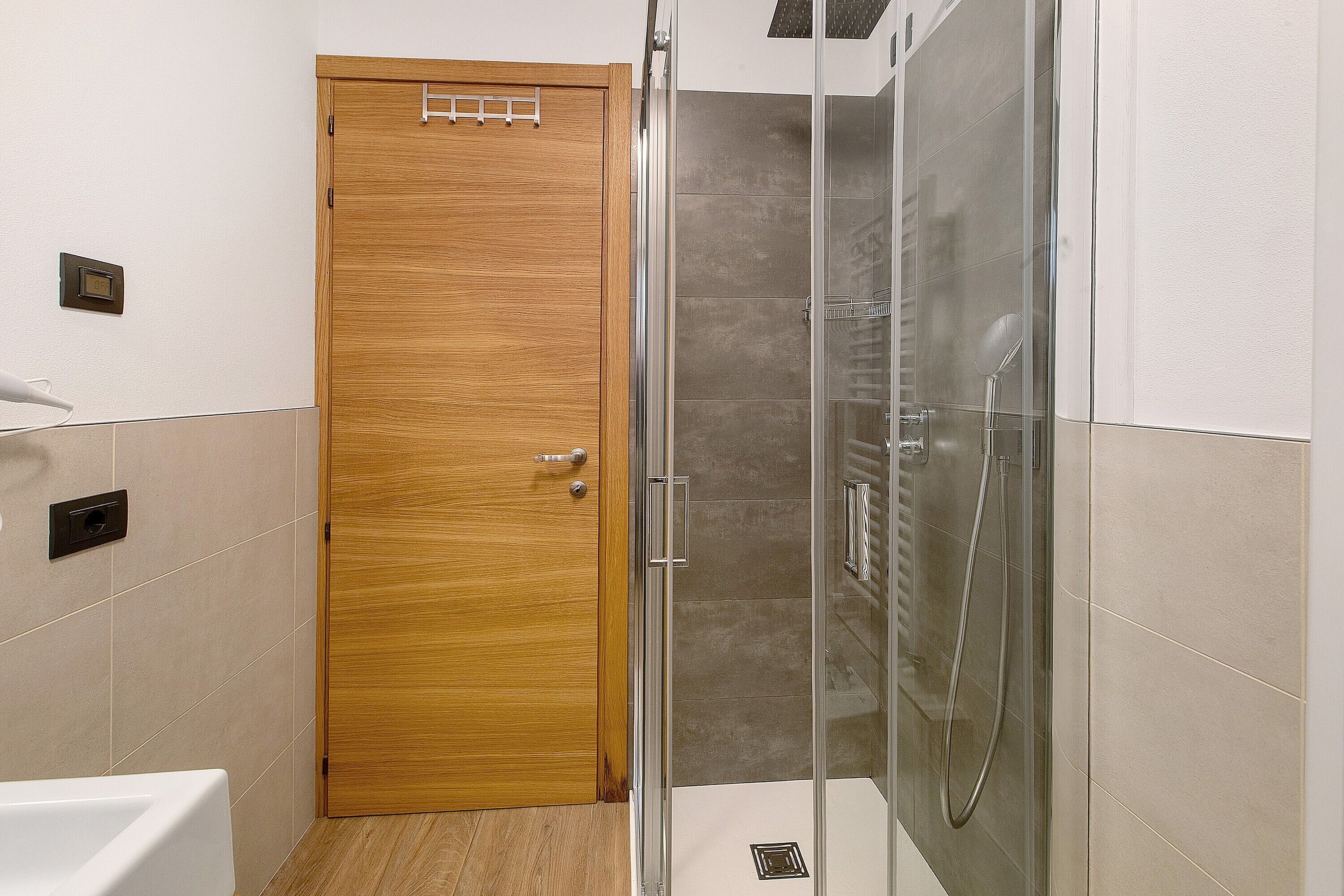 A bathroom with a wooden door, a glass shower enclosure, and a white bathtub.