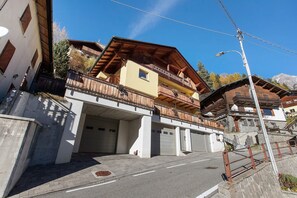 Un immeuble à plusieurs étages doté d’un balcon, de portes de garage et donnant sur la rue.