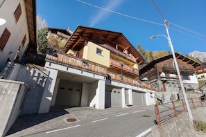 A multi-story building with a balcony, garage doors, and a street view.