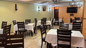 A restaurant with multiple tables and chairs, a flat-screen TV mounted on the wall, and a chandelier. - The Victorian Hotel Marsabit (Marsabit)