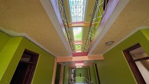 A multi-level interior with a central staircase, green walls, and a skylight. - The Victorian Hotel Marsabit (Marsabit)