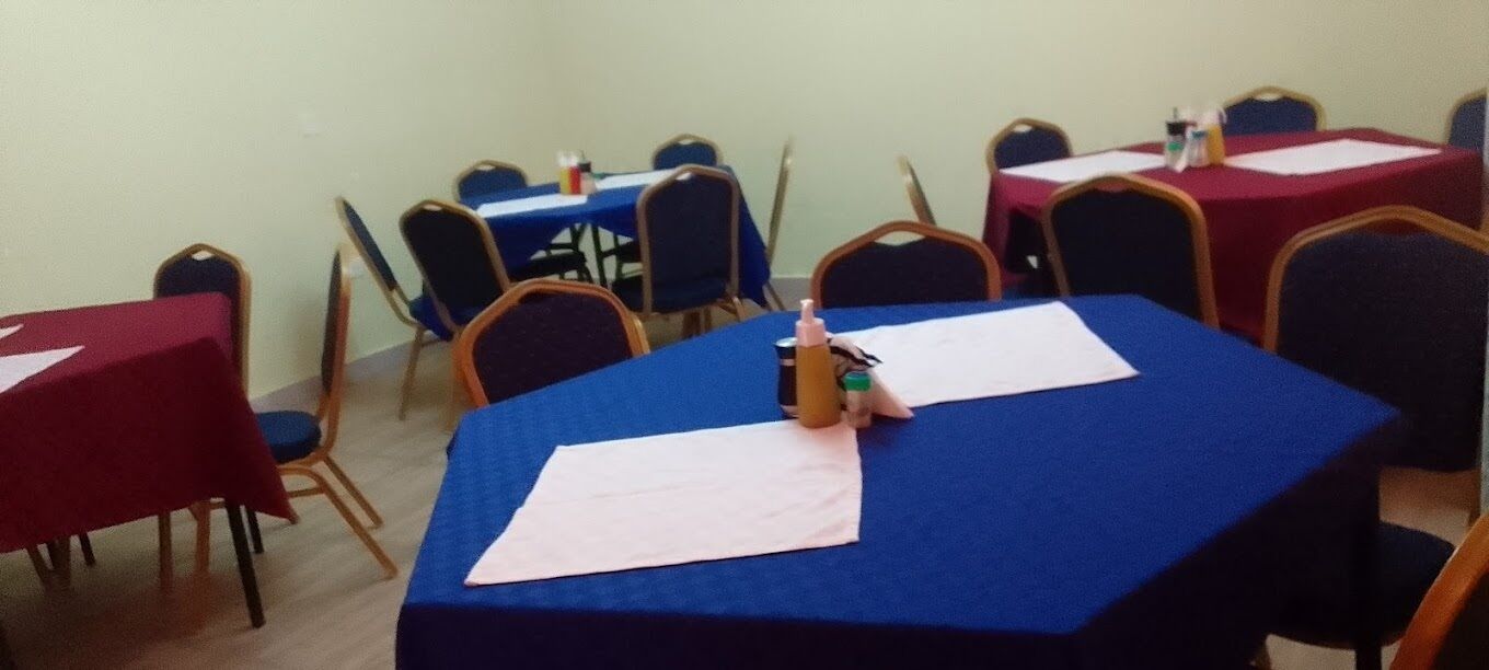 A conference room with tables covered in blue tablecloths, arranged in a U-shape.