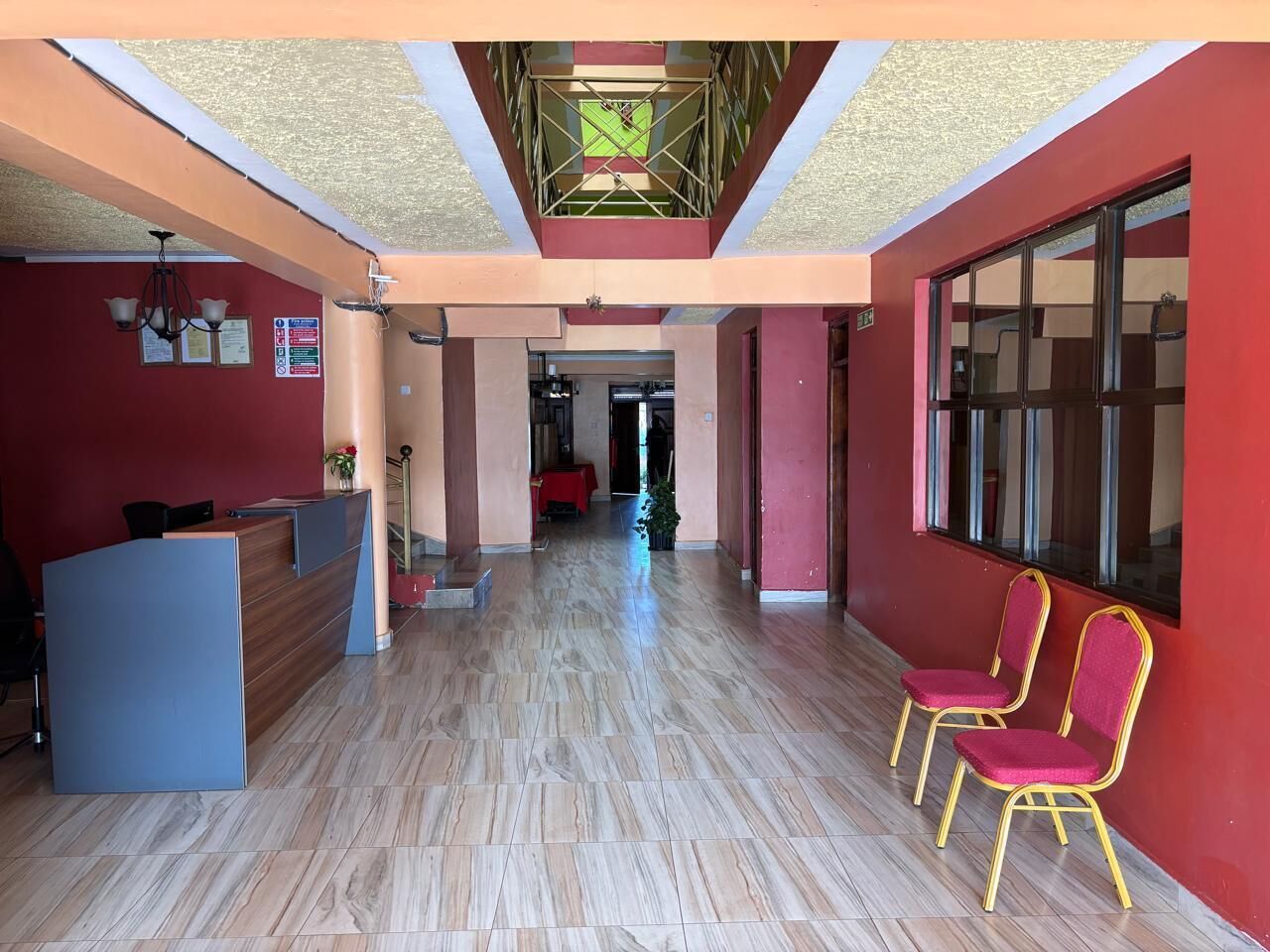 A reception area with a desk, chairs, and a staircase leading to a dining area.