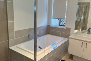 A modern bathroom with a glass-enclosed shower, a bathtub, and a vanity with a sink. - 4 Bedroom House, Master with ensuite and A/C (Flagstone)