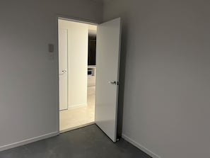 Un pasillo con una puerta blanca que da a una habitación con piso de baldosas.