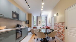 A modern kitchen with grey cabinets, a microwave, and a dining area with a round table and chairs.