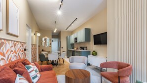 A modern living room with a sofa, armchairs, a coffee table, and a kitchen area in the background.