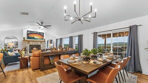 Un vaste espace de vie agrémenté d’une cheminée, d’une table à manger pouvant accueillir six personnes et d’une grande fenêtre offrant une vue sur l’extérieur.