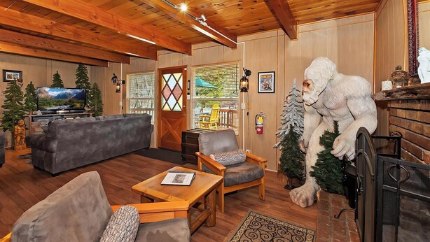 A cozy living room with a fireplace, a television, and a large statue.