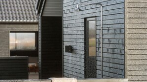 A showerhead with water flowing into a window, a towel hanging on the window sill, and a door leading to a room. - Lovely home in Idestrup with sauna (Idestrup)