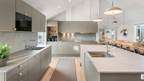 A modern kitchen with grey cabinetry, a large island with a sink, and pendant lighting. - Lovely home in Idestrup with sauna (Idestrup)