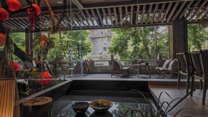 A traditional Japanese-style room with tatami flooring, a low table, and a view of a temple through large glass windows. - Shishe Spring Designer Homestay (Chengdu)