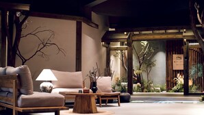 A cozy indoor seating area with a sofa, armchair, and coffee table, featuring a lamp and decorative vase. - Shishe Spring Designer Homestay (Chengdu)