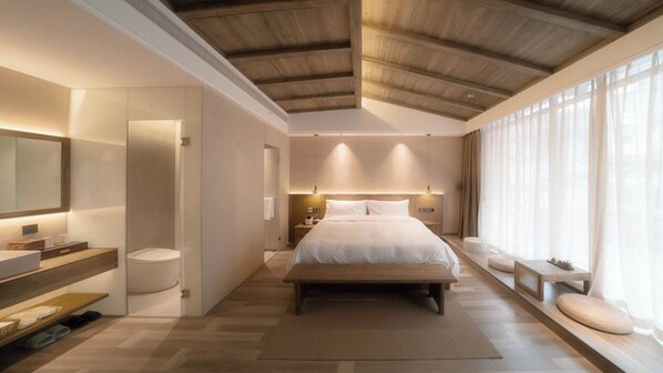 A modern bedroom with a large bed, a bedside table, a nightstand, a mirror, and a window with sheer curtains. - Shishe Spring Designer Homestay (Chengdu)