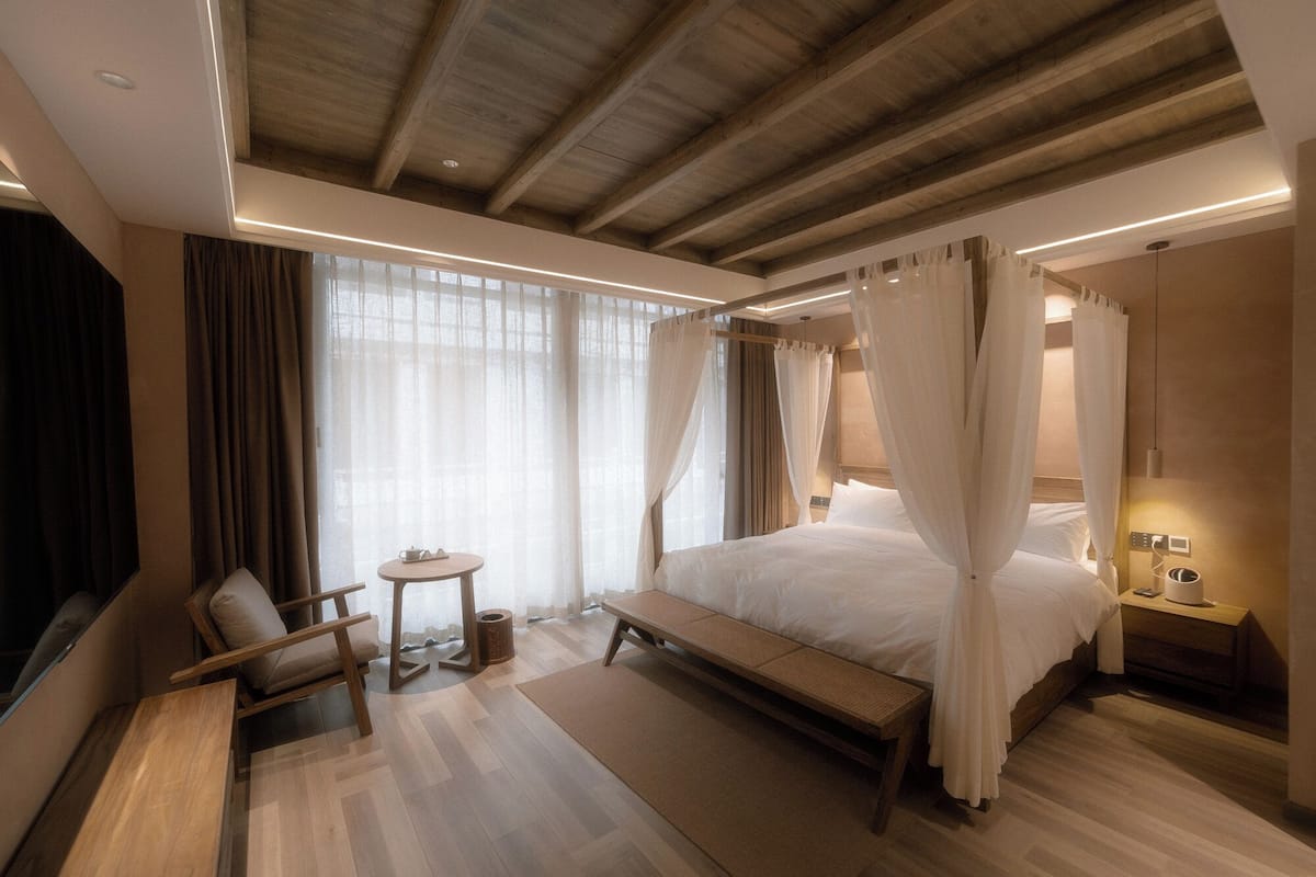 Ein Schlafzimmer mit einem großen Bett, einem Nachttisch, einem Sessel und einem kleinen Tisch.
