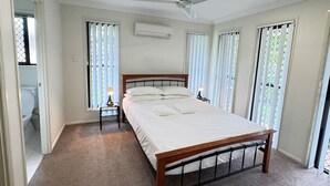 A bedroom with a bed, a ceiling fan, an air conditioning unit, and a window with blinds. - Beautiful 4 BDR House with ensuite and A/C (Redbank Plains)