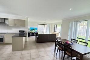 A modern kitchen with a dining area, a sofa, and a TV.