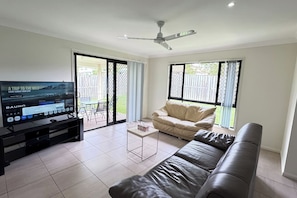 A living room with a TV, a sofa, a coffee table, and a ceiling fan.