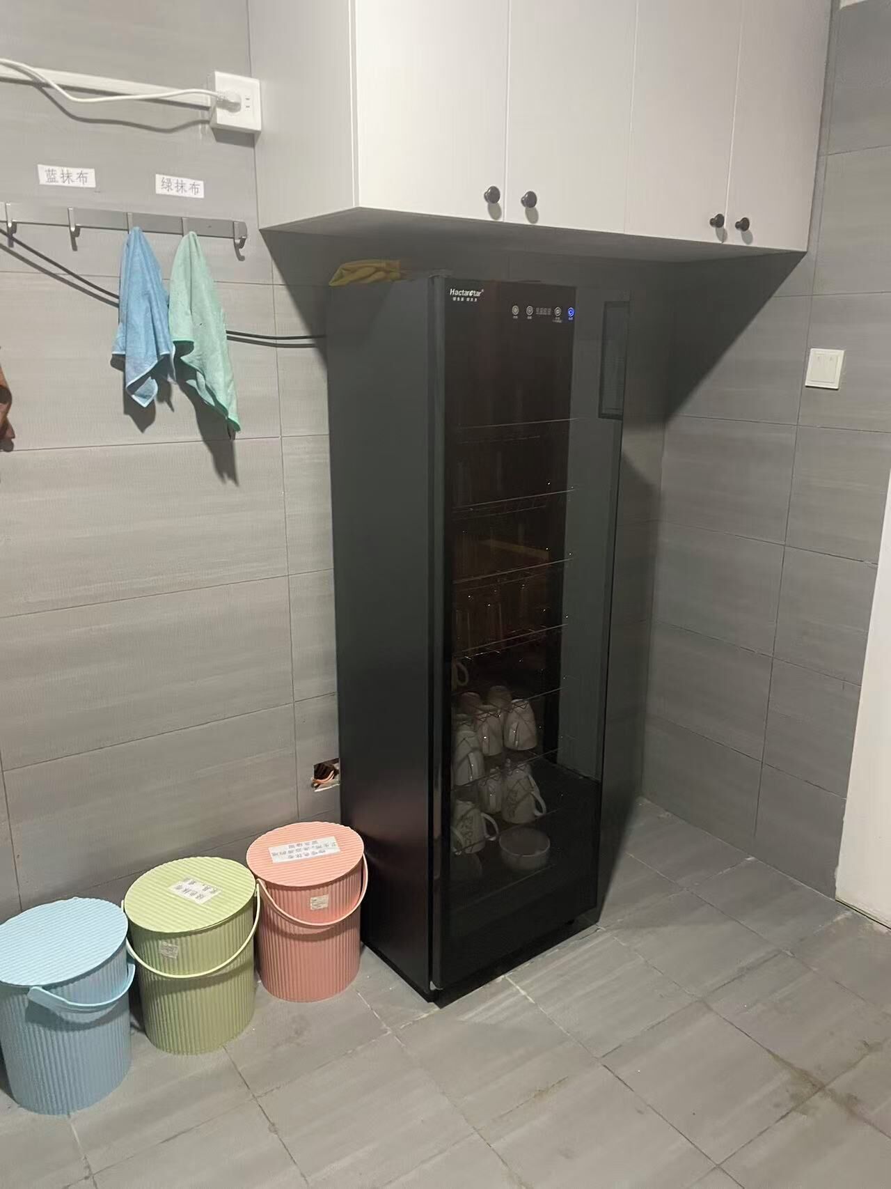 Habitación compacta con un mueble negro de almacenaje, una mesita pequeña y tres cubos de basura.